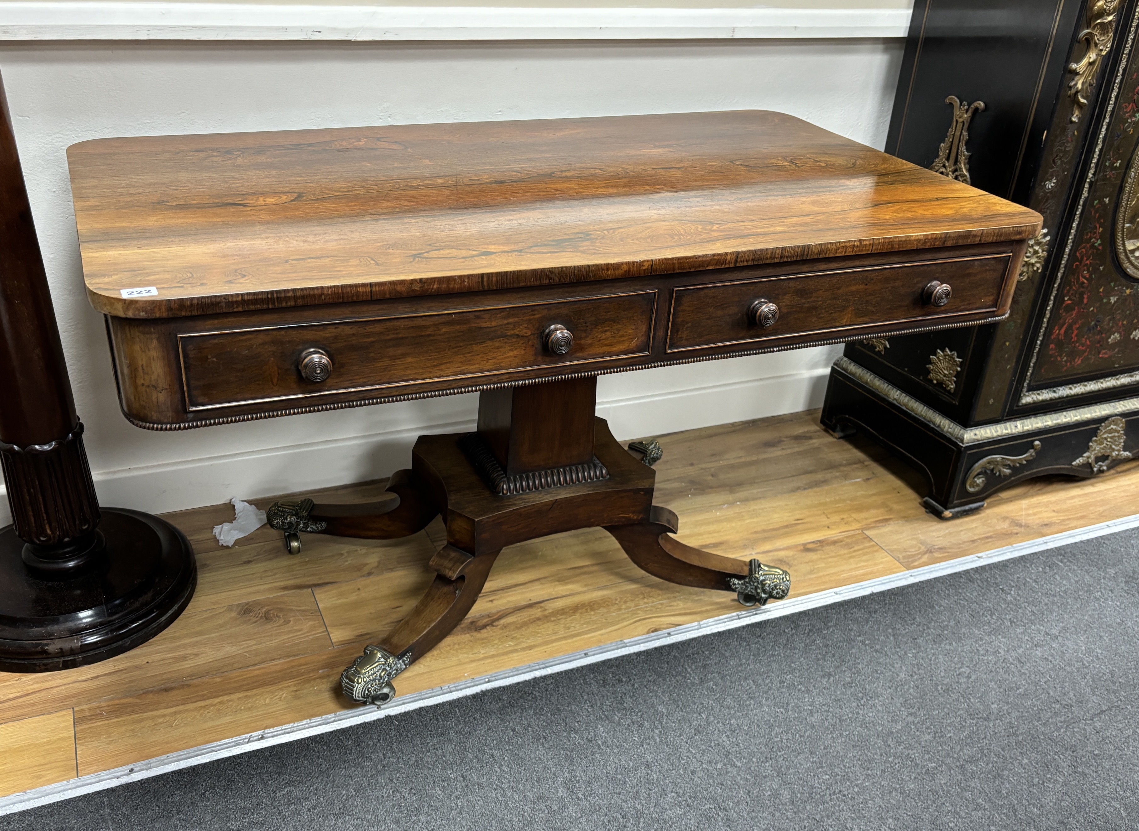 A Regency rectangular rosewood centre / library table, fitted two frieze drawers and two dummy drawers on single square tapered support, quadrapartite slab base and splayed legs with brass castors, width 123cm, depth 70c